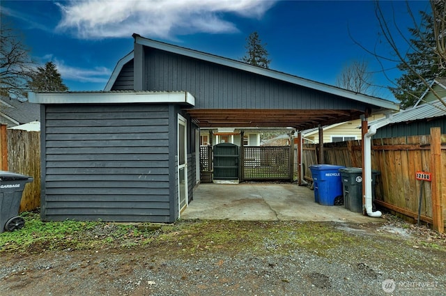 view of outdoor structure with fence and a carport