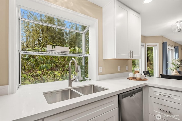 kitchen featuring light countertops, dishwasher, a sink, and white cabinetry