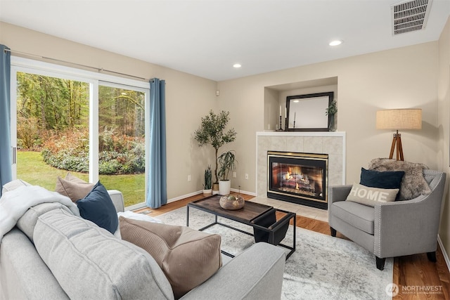 living area with light wood finished floors, baseboards, visible vents, a fireplace, and recessed lighting