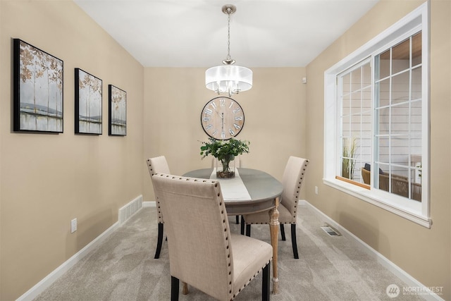 dining space featuring baseboards, visible vents, and light colored carpet