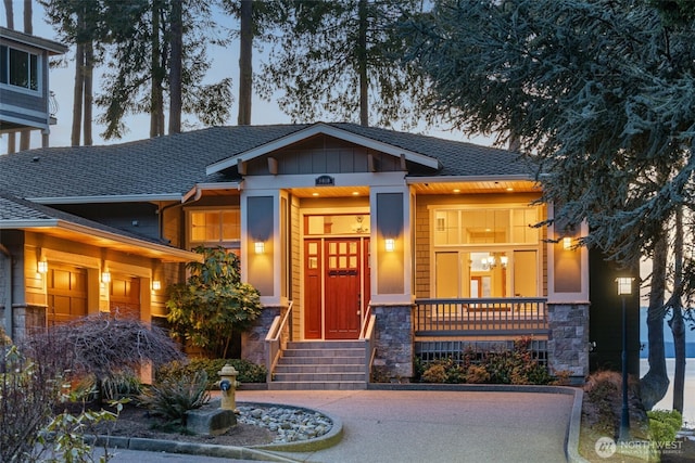 view of front facade with a garage, a shingled roof, driveway, stone siding, and board and batten siding