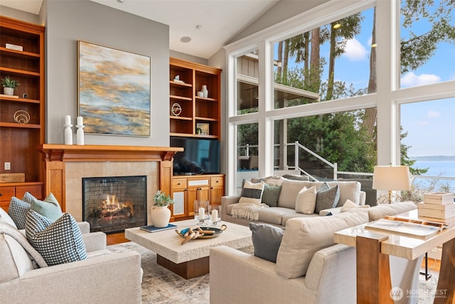 living area with a wealth of natural light, a tiled fireplace, and wood finished floors