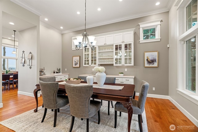 dining area featuring light wood-style floors, baseboards, a chandelier, and crown molding