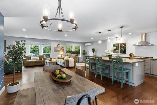 dining room with an AC wall unit, dark wood-type flooring, recessed lighting, and an inviting chandelier