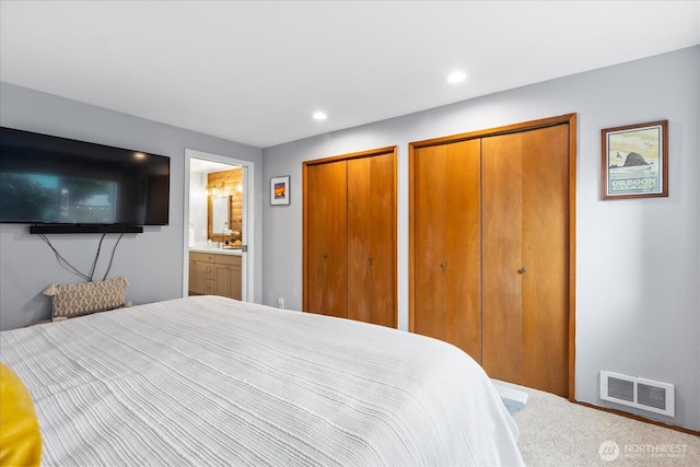 bedroom with recessed lighting, visible vents, connected bathroom, and two closets