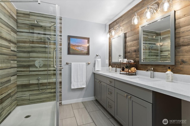 bathroom with a stall shower, a sink, baseboards, and double vanity