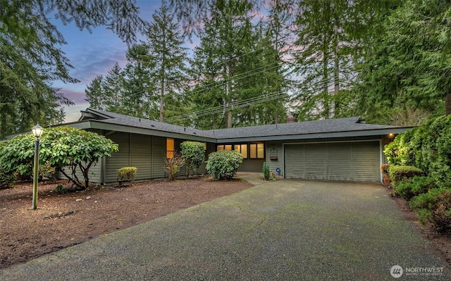 mid-century modern home with a garage and aphalt driveway