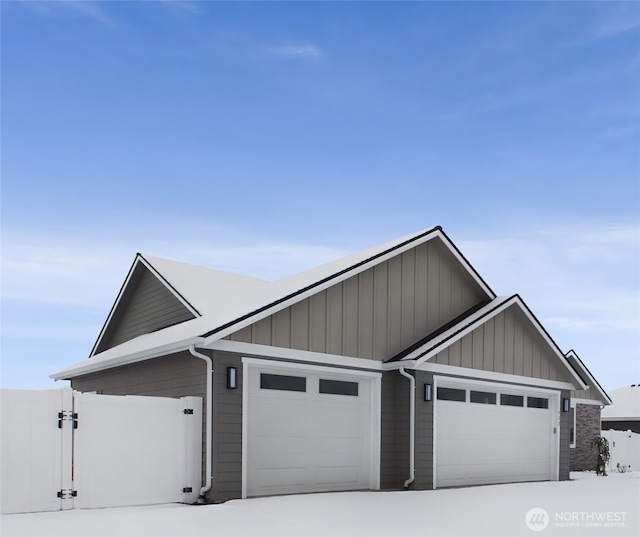 view of front facade with board and batten siding, an attached garage, and a gate