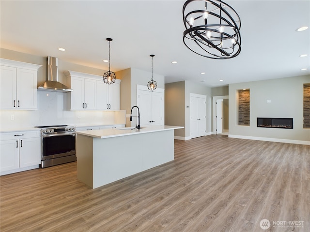 kitchen with stainless steel range with electric cooktop, light countertops, wall chimney exhaust hood, and white cabinetry