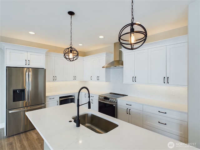 kitchen featuring appliances with stainless steel finishes, pendant lighting, white cabinets, and wall chimney exhaust hood