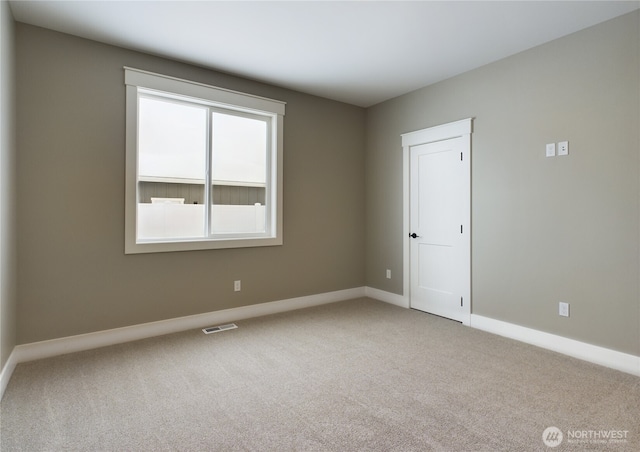 carpeted empty room featuring baseboards and visible vents