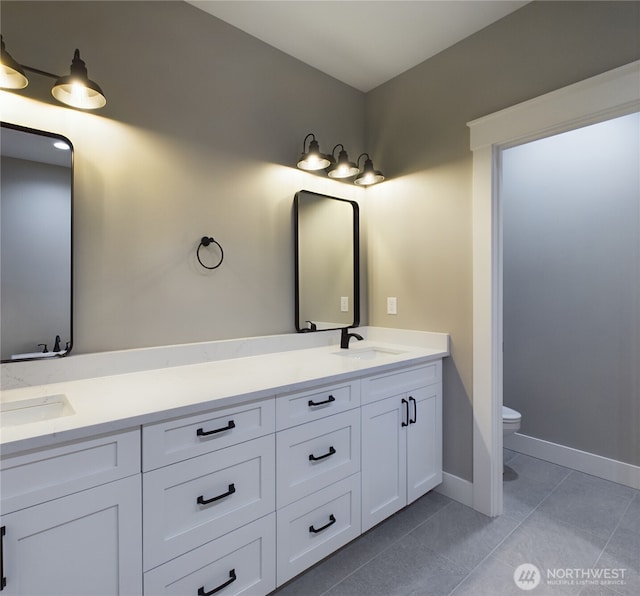 bathroom with double vanity, a sink, toilet, and tile patterned floors