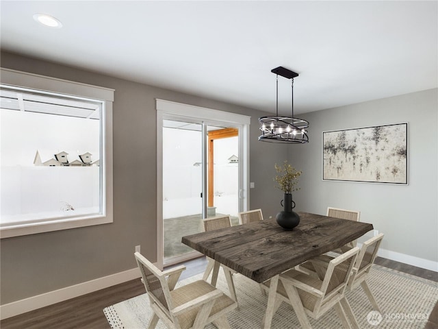 dining area with a chandelier, dark wood finished floors, and baseboards