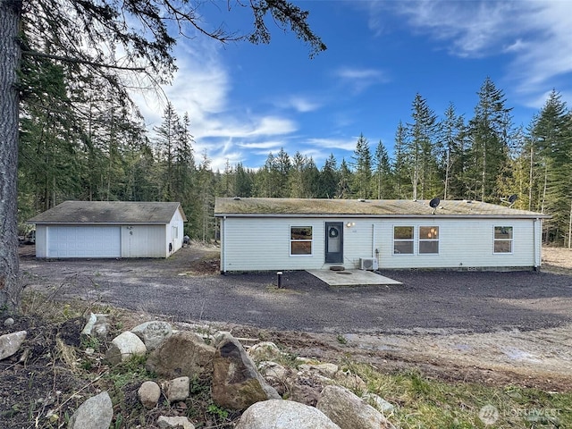 manufactured / mobile home with a garage, a wooded view, and an outbuilding