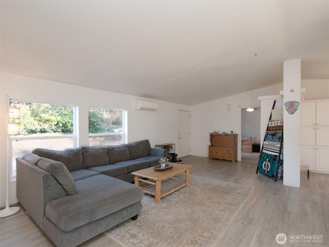 living room featuring vaulted ceiling, an AC wall unit, and light wood-type flooring