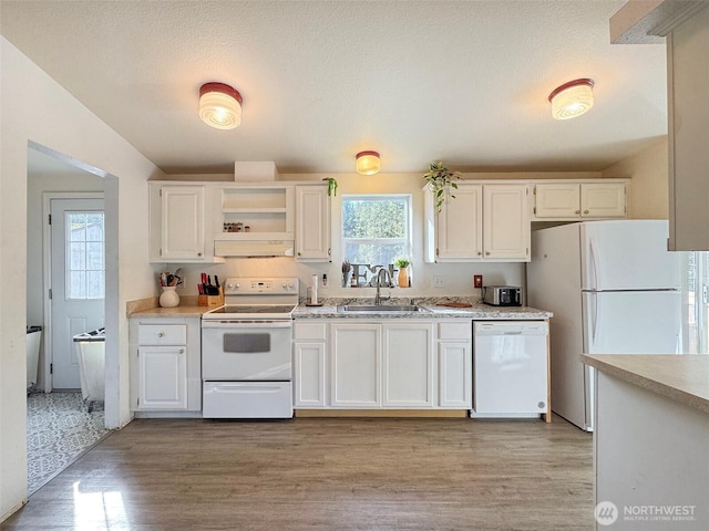 kitchen with white appliances, white cabinets, light countertops, under cabinet range hood, and a sink