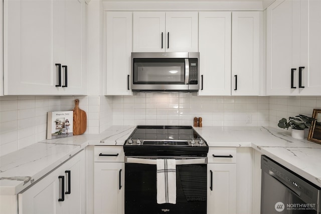 kitchen with stainless steel appliances, tasteful backsplash, white cabinetry, and light stone countertops