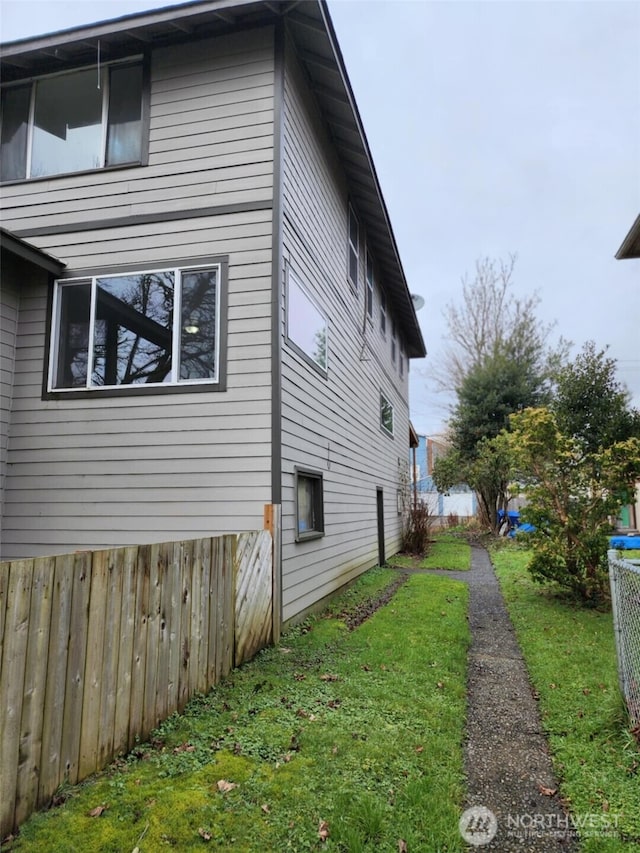 view of side of home featuring fence and a lawn