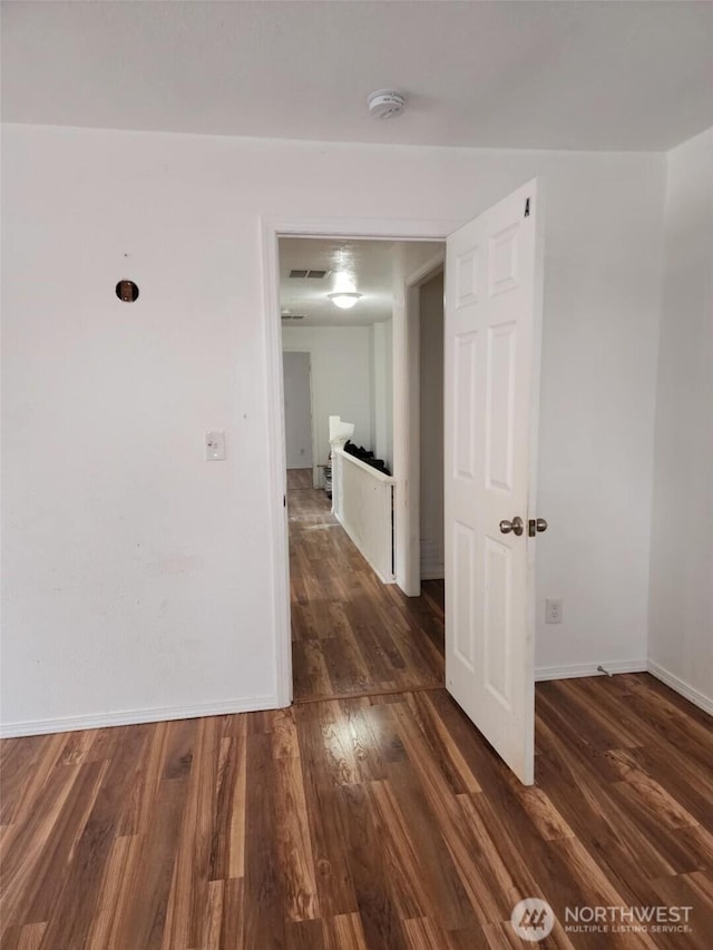 corridor with dark wood-style flooring and baseboards