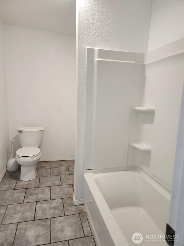 bathroom with shower / tub combination, toilet, and baseboards