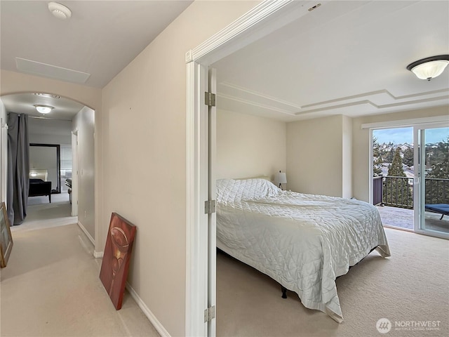 bedroom featuring arched walkways, baseboards, carpet flooring, and access to exterior