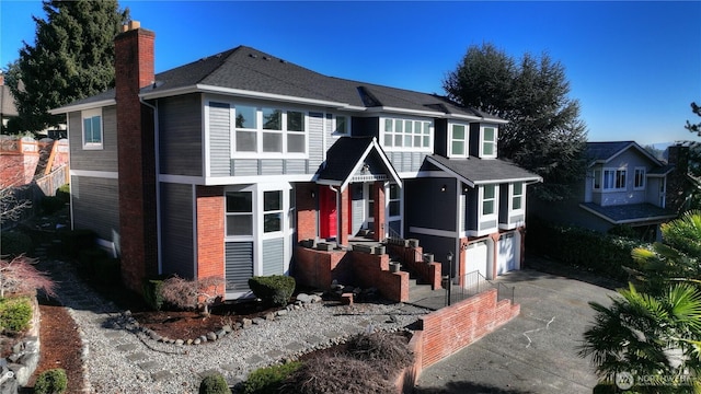 view of front of house with an attached garage, concrete driveway, and a chimney