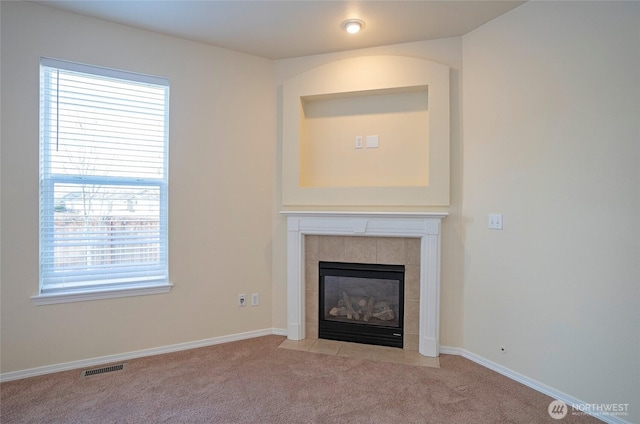 unfurnished living room featuring light colored carpet, a fireplace, visible vents, and baseboards