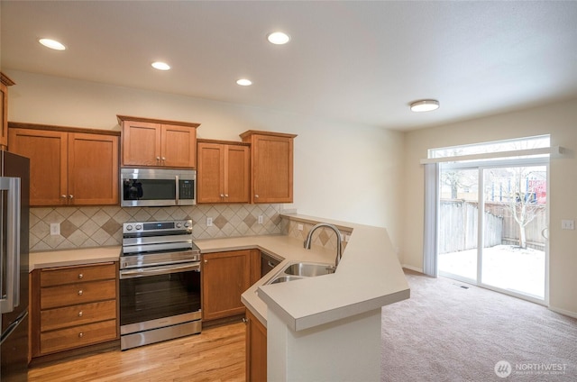 kitchen featuring a sink, brown cabinets, stainless steel appliances, and light countertops