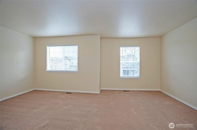 unfurnished room with light colored carpet, visible vents, and baseboards