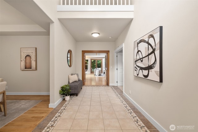 hall featuring light tile patterned floors and baseboards