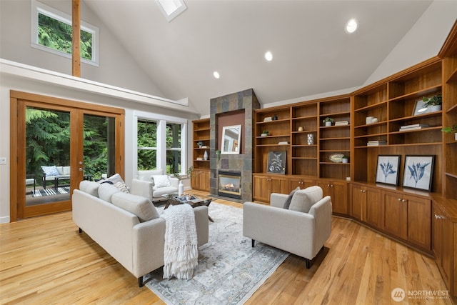 living area with plenty of natural light, light wood-style flooring, a tiled fireplace, and french doors