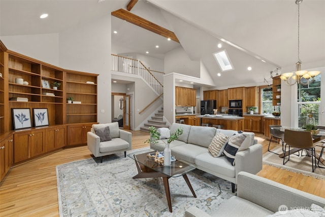 living room featuring vaulted ceiling with skylight, stairway, light wood-type flooring, and an inviting chandelier