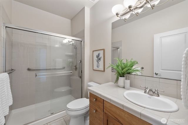 bathroom with a stall shower, toilet, tile patterned floors, vanity, and a chandelier