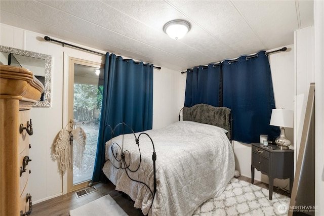 bedroom with access to outside, visible vents, and wood finished floors