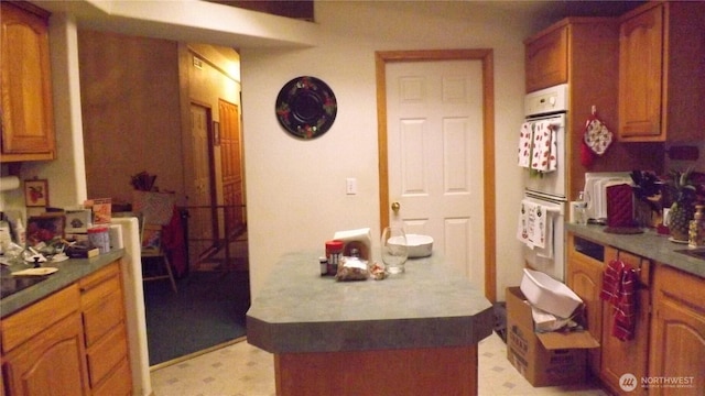 kitchen featuring double oven, brown cabinets, and light floors