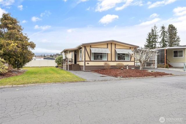 manufactured / mobile home featuring driveway, a front yard, and fence