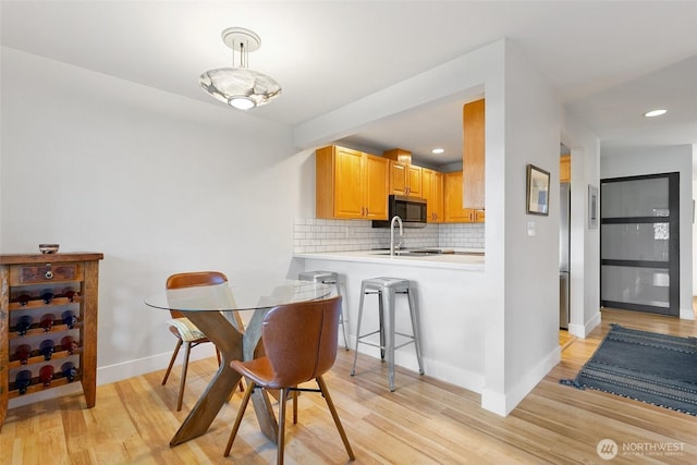 dining room featuring baseboards, recessed lighting, and light wood-style floors