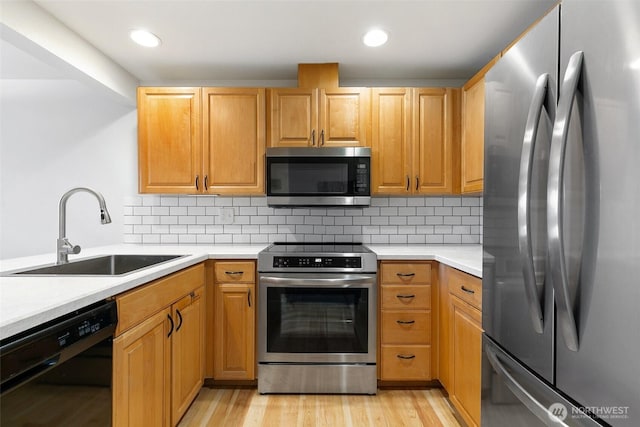 kitchen featuring stainless steel appliances, backsplash, a sink, and light countertops