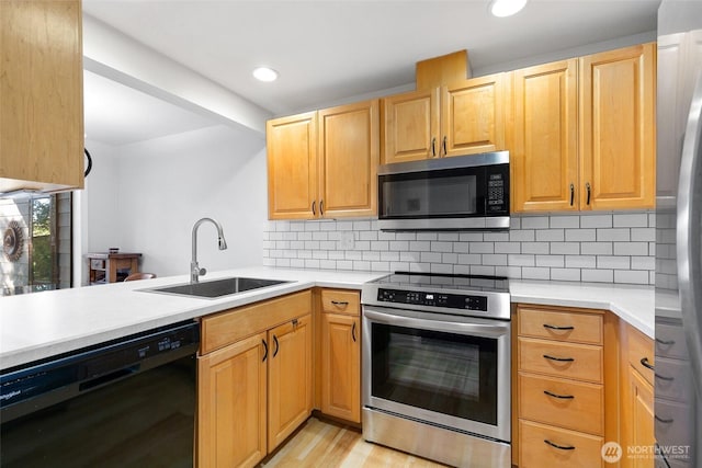 kitchen with appliances with stainless steel finishes, a sink, light countertops, backsplash, and recessed lighting