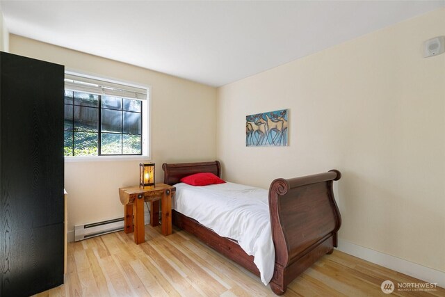 bedroom featuring a baseboard radiator, wood finished floors, and baseboards