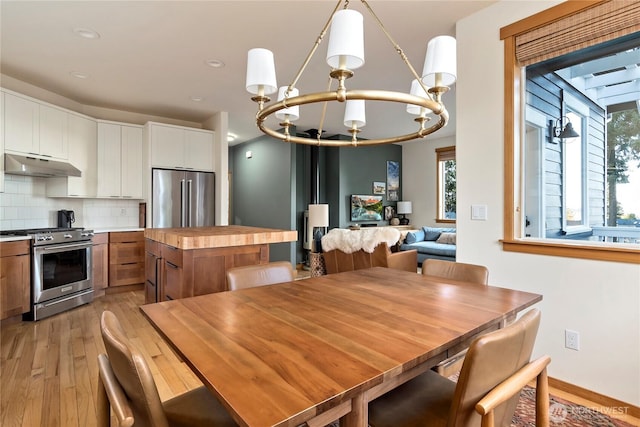 dining area featuring light wood-style flooring, a chandelier, baseboards, and recessed lighting