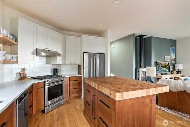 kitchen with a kitchen island, stainless steel appliances, under cabinet range hood, white cabinetry, and open shelves