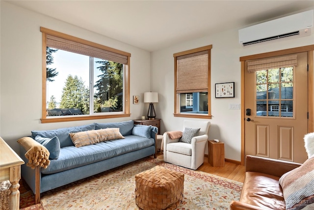 living area with baseboards, a wall unit AC, a wealth of natural light, and light wood-style floors