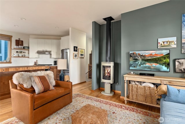 living room with a wood stove and light wood-style flooring