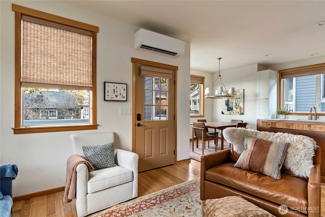 living room with light wood finished floors, an inviting chandelier, a wealth of natural light, and a wall mounted air conditioner