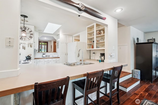 kitchen with open shelves, light countertops, white cabinetry, a sink, and a peninsula