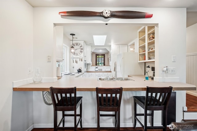 kitchen featuring a peninsula, light countertops, a sink, and freestanding refrigerator