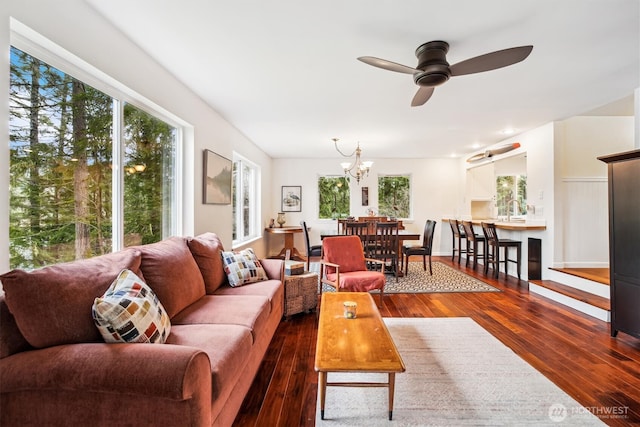 living room featuring dark wood-style flooring and ceiling fan with notable chandelier