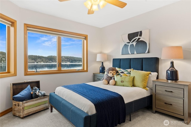 bedroom with ceiling fan, a water view, baseboards, and light colored carpet