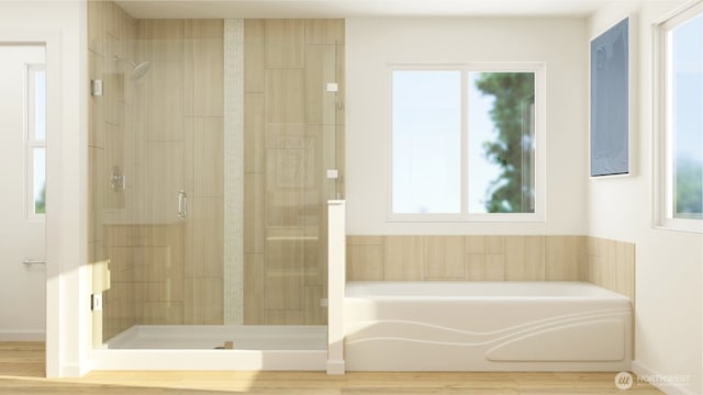 full bathroom featuring a garden tub, a shower stall, and wood finished floors